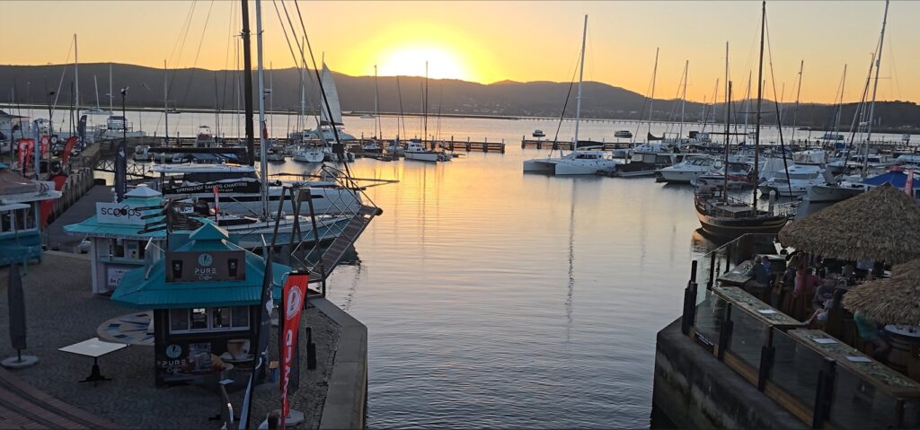 Golden sunset reflecting on the calm waters of Knysna Lagoon with silhouetted hills in the distance on the 4 Day Garden Route Group Tour